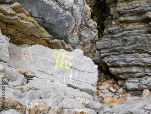 Fotografie Yellow graffiti text painted limestone coastal rock Budva Montenegro