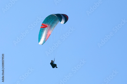 Vol en parapente dans un ciel bleu azur d'été en montagne. Voile multicolore. 