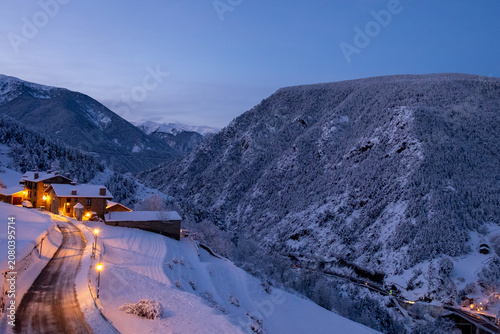 Photos Charming mountain village at blue hour in winter, snowy landscape with warm stre
