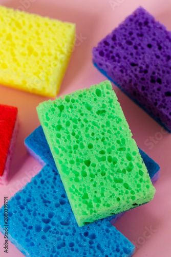 Multicolored foam scrubbers on a bold pink backdrop, representing effective cleaning solutions, hygiene products, and household routines.
