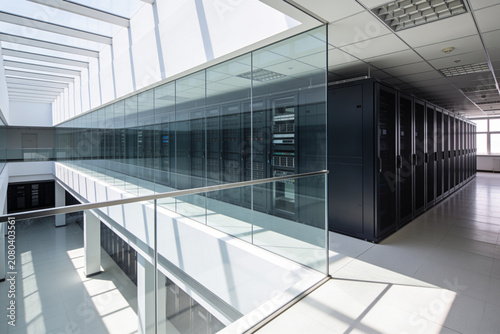 Tableau sur toile Modern data center with rows of server racks behind glass walls