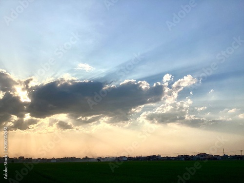 sunlight shining through the gaps in the black clouds, a beautiful sunset in the rice field area