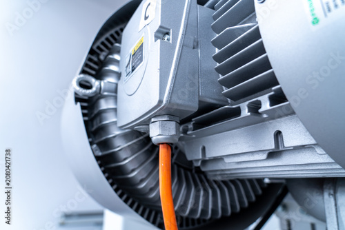Bild auf Leinwand Close-up of industrial electric motor with orange power cable and cooling fins