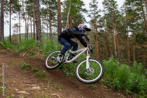 Athlete racer riding at speed on forest trail during downhill competition