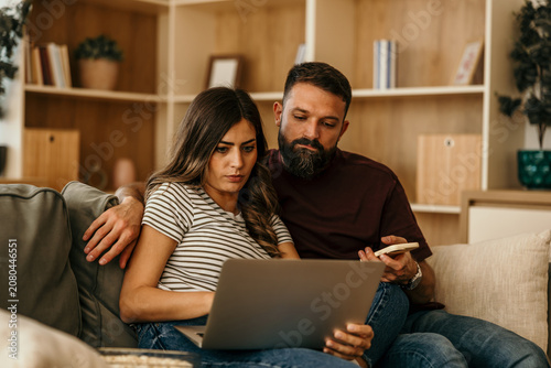 Vászonkép Couple concentrating on laptop for online banking at home