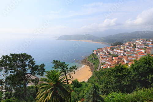 Aerial view of the charming town of Lastres with its white houses, bay, and mountains on a hazy day in Asturias, Spain