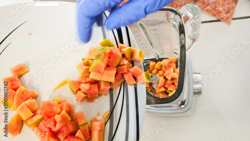 Laboratory technician transferring diced papaya sample into laboratory blender during food analysis and GMO testing preparation