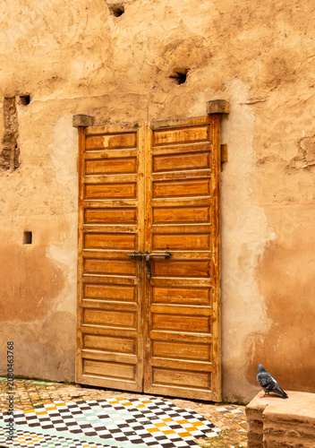 Traditional Wooden Door and Adobe Wall of a Historic Medieval Royal Palace in Marrakech, Morocco