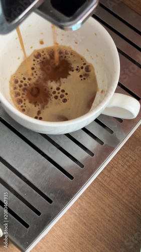 Freshly brewed espresso coffee pouring into a white cup