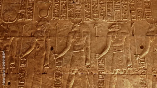 Intricate stone carvings and hieroglyphics depicting Egyptian deities on the walls of the hypostyle hall at the Temple of Edfu in Egypt.
