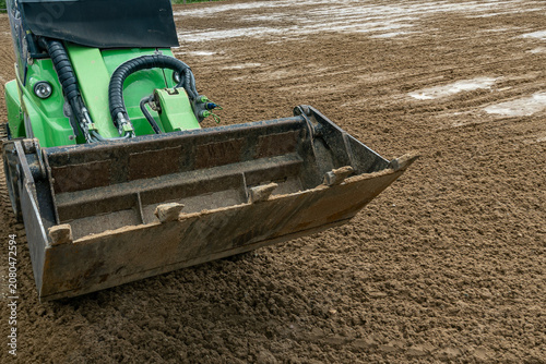 Mini loader levelling quartz sand surface on equestrian arena outdoor horse riding ring footing installation and maintenance process