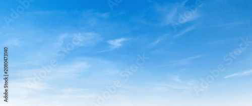 Clear blue sky with wispy, soft clouds drifting gently
