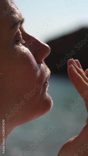 Sunscreen skincare protection woman applying moisturizing facial cream outdoors in bright sunlight at the beach to prevent sun damage during summer