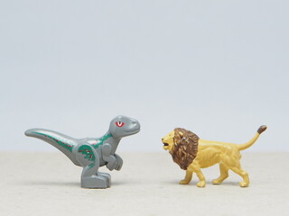 Mini toy of action figure at table with blur background. Miniature photography concept design. Minifigure of Dinosaurs and Lion character. Animal at wildlife.