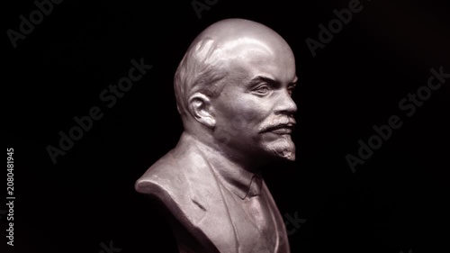 Metal bust of Lenin rotating in dramatic light, historical sculpture close-up