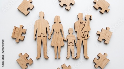 Wooden Family Figures Formed From Jigsaw Puzzle Pieces on a Clean White Surface