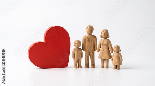 Wooden figures of a happy family standing next to a large red heart symbol of love