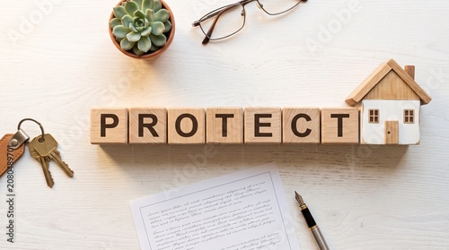Wooden Blocks With Protect Word and Miniature House Representing Real Estate Security and Home Insurance Concepts