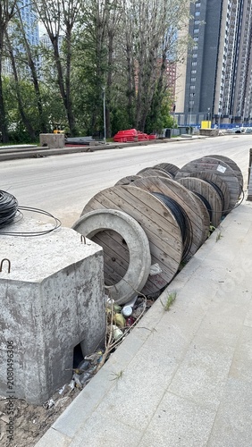 Wooden cable reels stored along urban road construction site with infrastructure materials prepared for utility installation