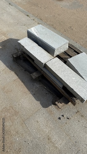 Granite curb stones stacked on wooden pallet at construction site ready for urban infrastructure installation