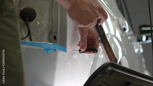 Paintless Car Dent Repair. Process of paintless dent repair on car body. PDR. The mechanic at the auto shop with tools to repair dents in car body. Body repair. A specialist repairs a dent on the car.