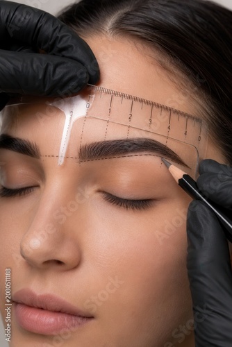 Precise eyebrow mapping measurement with ruler and pencil for professional brow shaping procedure