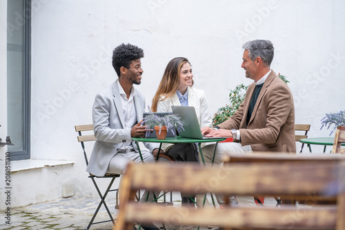 three business people having a meeting for a briefing outside the office with laptop and tablet