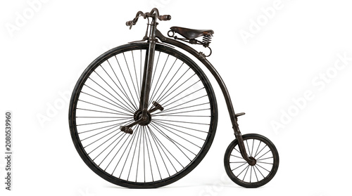 Authentic historical high wheel bicycle side view, showcasing the primitive pedal drive and unique geometry of a late 1800s transport vehicle used by early cyclists and Victorian gentlemen.
