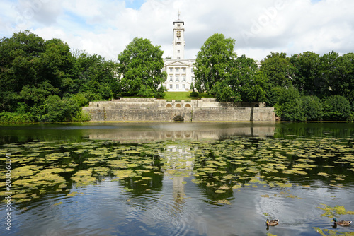 Scenic View Of Trent Building At University Of Nottingham Reflected In Highfields Park Lake With Ducks And Green Plants Under A Cloudy Sky In Nottingham, England.