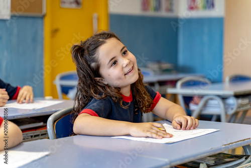 Young girl smiling and looking up, happily learning during class at elementary school. Focus on education and childhood development