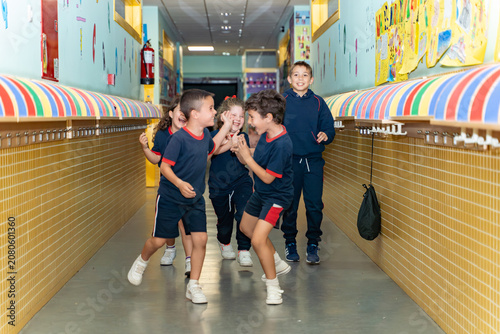 Happy children in uniform having fun during a break, running and interacting in a colorful school corridor