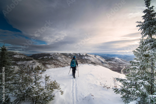 Single woman hiking Dome mountain in winter, walking in the fresh snow toward the edge, ZEC des martres, Charlevoix region, QC, Canada