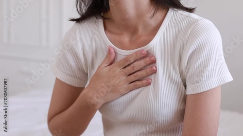 The young woman placed her hand over her breasts while touching them because of sudden physical pain or emotional stress.