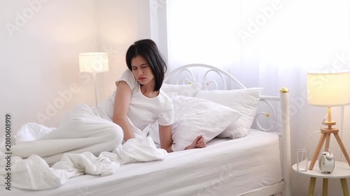 A young woman is waking up in bed (while sleeping). She is stretching her arms in the refreshing morning air, peacefully relaxing in her morning routine.