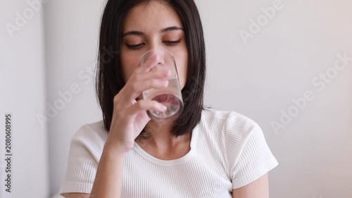 A woman waking up and drinking plain water for good health in the morning. A health-conscious idea.