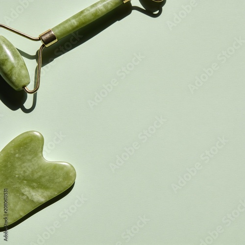 A serene composition featuring a jade facial roller and gua sha tool on a pastel green surface, bathed in soft, diffused light, evoking a sense of tranquility and self-care