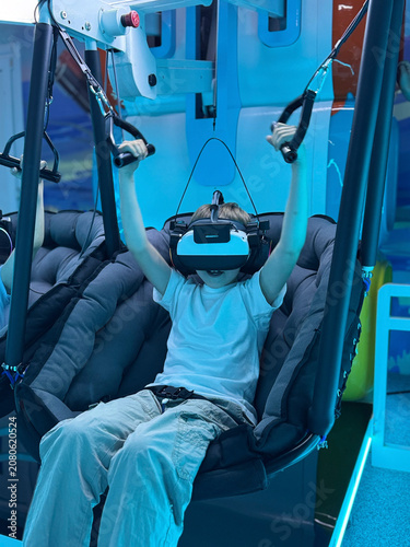 Boy enjoying a virtual reality simulator ride in a futuristic entertainment venue.