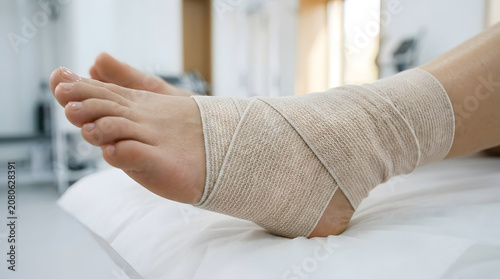 Close-up of a firm white compression bandage or elastic wrap applied securely around a patient's foot arch and midfoot for swelling control and support