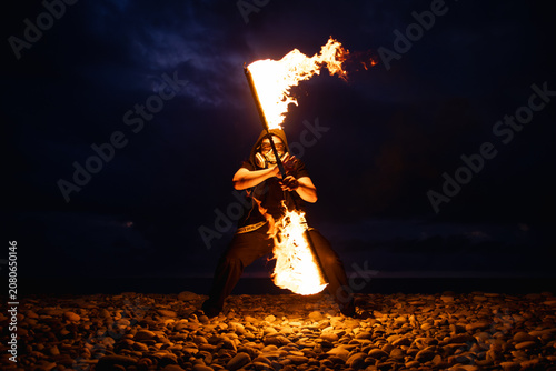 Fire performer with burning torches at night