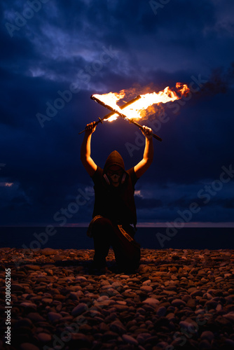 Fire performer with burning torches at night