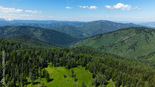 Foto Scenic drone aerial rising shot flying over green forested slopes, revealing an endless panorama of majestic Altai mountains under a blue sky
