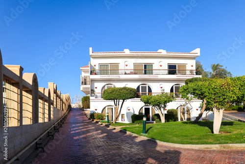Modern residential apartment building surrounded by palm trees an Arab country under clear blue sky.