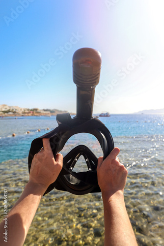 Canvas Print Woman holding a snorkeling mask up against bright blue sky with the sea background