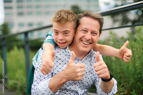 cute little child with trisomy 21 syndrome outside in summer season with his father