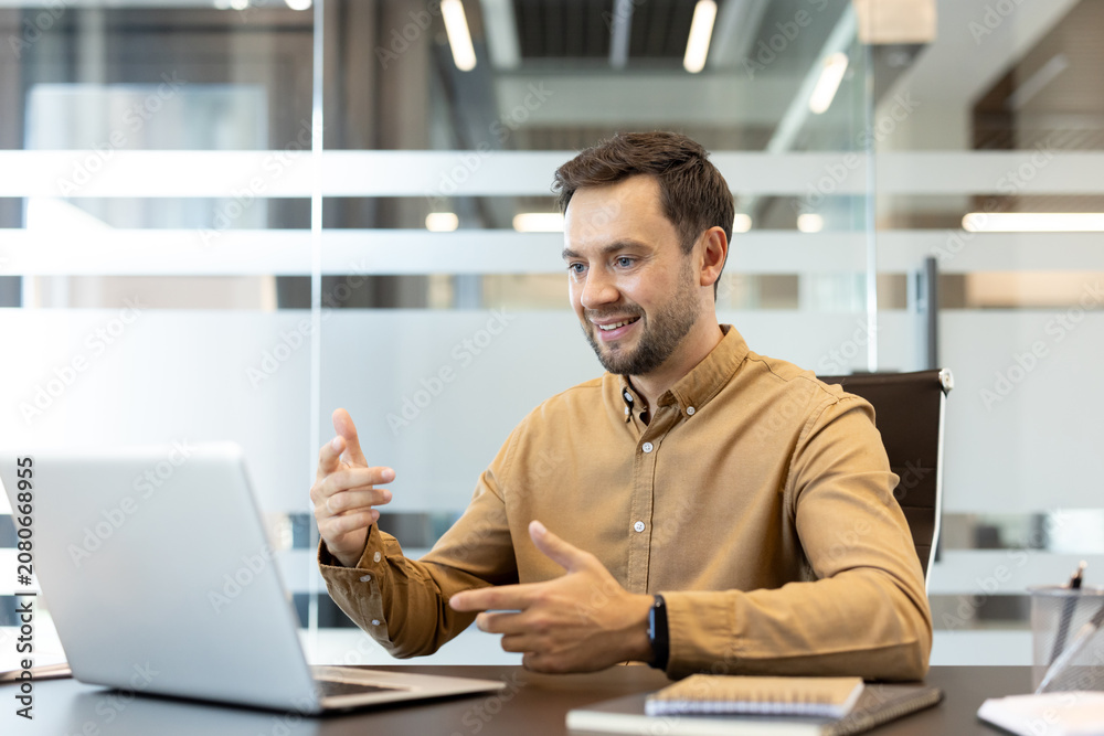 Obraz premium Business man interacting during a video call on a laptop, engaging online with clients or team members from a modern office workspace
