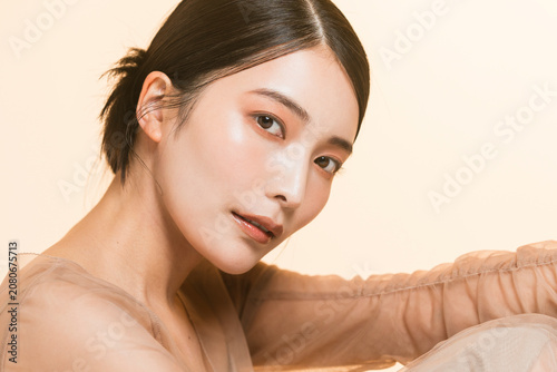 фотографія ベージュのオーガンジーのドレスを着たカメラ目線の日本人女性のツヤ肌ビューティーポートレート