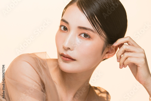 фотографія ベージュのオーガンジーのドレスを着たカメラ目線の日本人女性のツヤ肌ビューティーポートレート