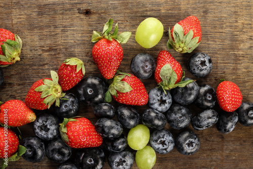 Fresh ripe Blueberry strawberry grape macro closeup on wood dark white background