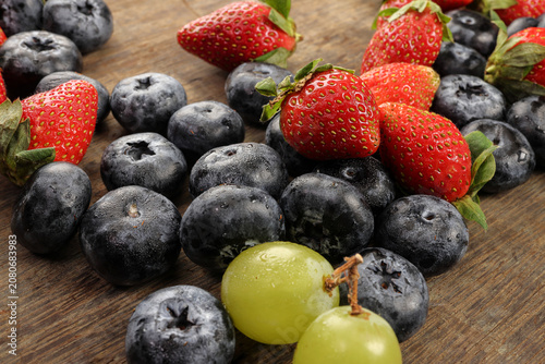 Fresh ripe Blueberry strawberry grape macro closeup on wood dark white background