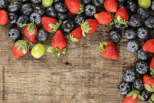 Fresh ripe Blueberry strawberry grape macro closeup on wood dark white background